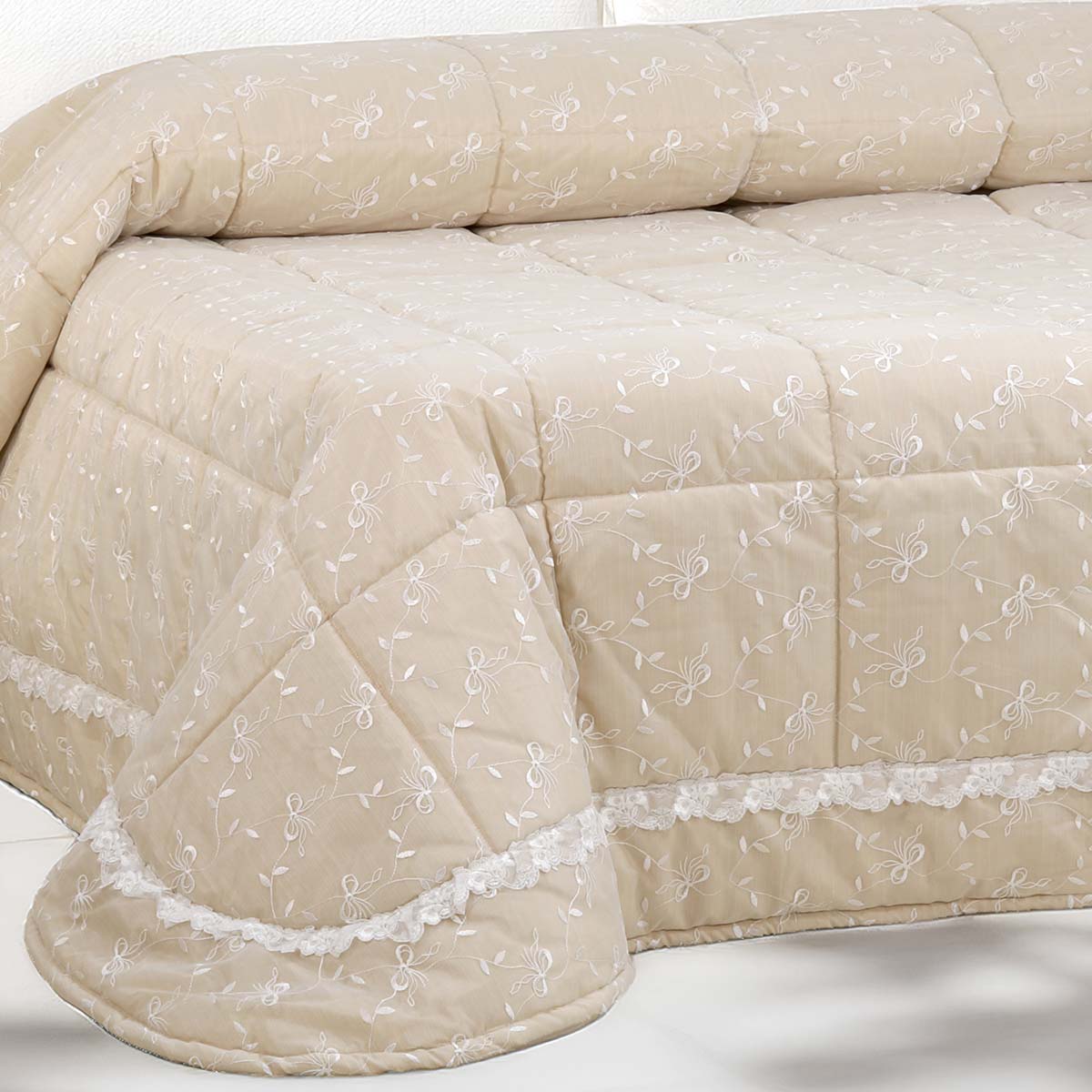 Trapunta letto matrimoniale di colore beige con ricami floreali bianchi e balza in pizzo, imbottitura anallergica Made in Italy.