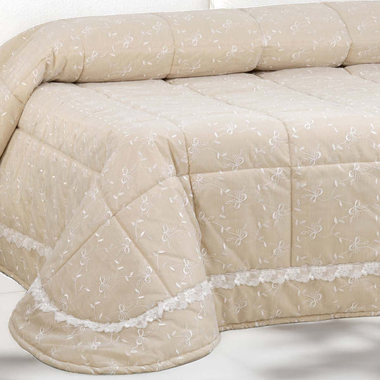 Trapunta letto matrimoniale di colore beige con ricami floreali bianchi e balza in pizzo, imbottitura anallergica Made in Italy.